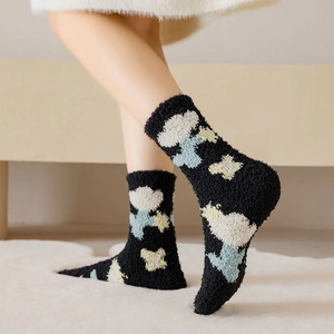 Detailed close-up of thick black coral fleece socks with cute cloud and star patterns