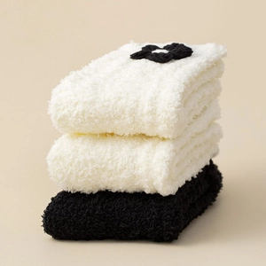 Close-up of thick coral fleece socks with flower patterns in white and black