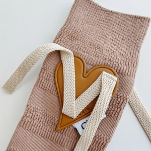 Detailed macro of pink ribbed knit socks featuring a heart leather patch and cotton drawstring