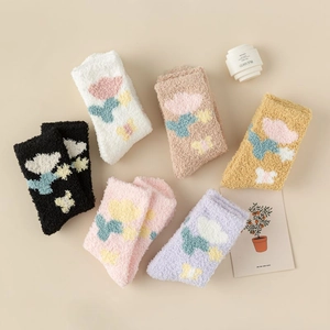 Flat lay detail of 6 pairs of thick coral fleece socks with colorful floral patterns