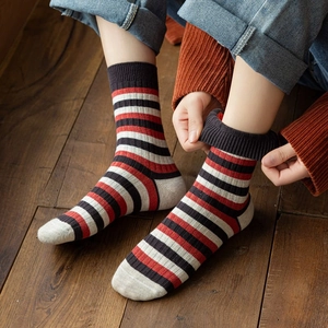 Detail of red and black striped cotton crew socks paired with denim and cozy knitwear