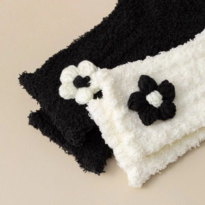 Detailed view of plush coral fleece knit socks with decorative white floral accents