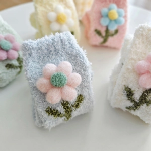 Nahaufnahme dicker Korallenvlies-Socken mit 3D-Plüschblumen in sanften Pastellfarben