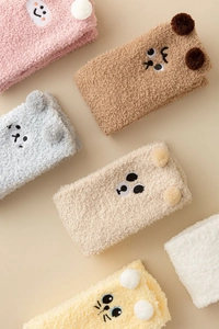 Detail of coral fleece winter socks with cute animal embroidery and 3D pompoms