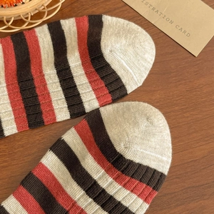 Macro shot of striped cotton socks in red and brown on a rustic wooden background