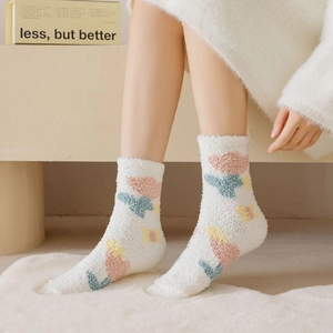 Close-up of thick coral fleece winter socks with tulip pattern on soft plush rug