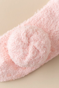 Detail of pink coral fleece thermal socks with fluffy ball and non-slip rubber dots