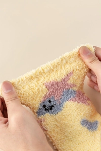 Close-up of thick yellow coral fleece socks with high elasticity and cute cartoon pattern