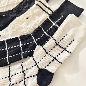 Black and beige mid-calf knitted socks with minimalist argyle and cable stitch patterns