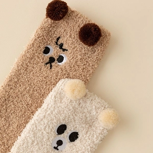 Close-up of thick coral fleece winter socks featuring cute 3D bear ears and embroidery
