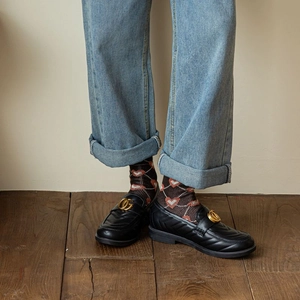 Classic black leather loafers with gold metal logo paired with heart patterned mid socks