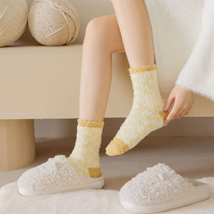 Close-up of yellow checkered coral fleece socks and white fuzzy slippers for winter