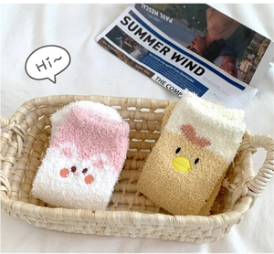 Details der dicken Korallenfleece-Socken mit süßen Comic-Gesichtern in einem Korb