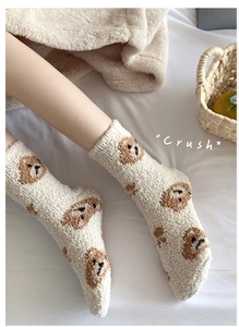 Detail of coral fleece winter socks with cute bear pattern on white bedding background