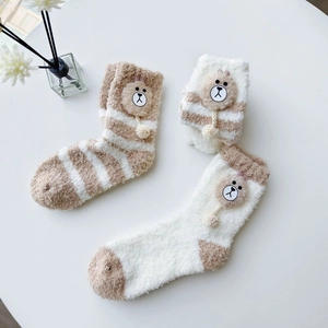 Detail of soft coral fleece socks with cute cartoon bear ornaments and fluffy texture