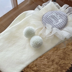 Detail of white rib knit socks featuring a grey cat embroidery patch with lace and pom-poms