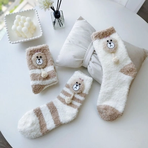Close-up of thick coral fleece winter socks with cute 3D plush bear ears and soft pom-poms
