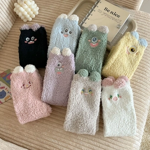 Flat lay of colorful coral fleece socks with cute cartoon monster faces and 3D ears
