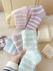 Close-up of soft coral fleece striped socks in assorted Morandi colors on white rug