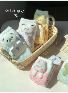 Detail of plush coral fleece socks featuring 3D cartoon animal designs in a basket