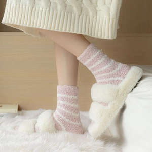 Close-up of pink striped thick coral fleece socks worn with fluffy white slippers