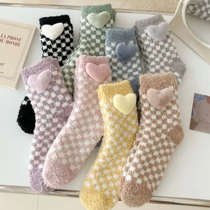 Close-up of checkerboard coral fleece socks with 3D plush hearts in multiple colors