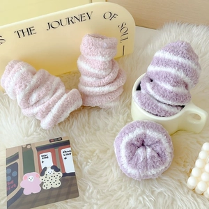 Soft pink and purple striped coral fleece socks in a cozy home setting on plush carpet