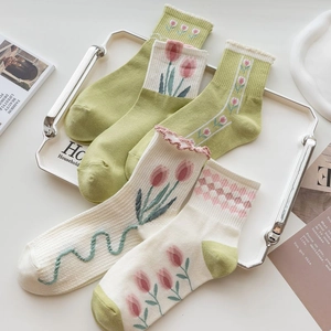 Flat lay of green and cream cotton crew socks with tulip patterns and ruffled cuffs