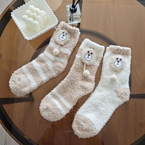 Detailed view of thick coral fleece socks with cute plush bear charms and fuzzy pom-poms