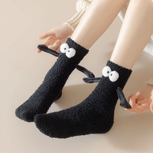 Détail de chaussettes en molleton corail noir avec yeux 3D et petites mains