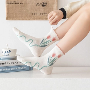 Detail of white cotton mid-calf socks featuring pink tulip floral prints and ruffled edges