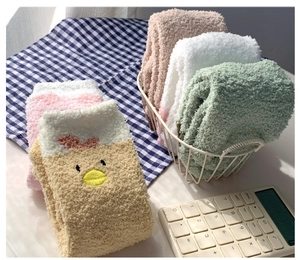 Nahaufnahme flauschiger Korallenvlies-Wintersocken mit niedlicher Tierstickerei im Korb