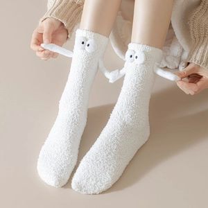 Détail de chaussettes blanches en molleton avec yeux 3D et design mains qui se tiennent