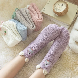 Close-up of fluffy coral fleece socks with cute cartoon embroidery for winter warmth