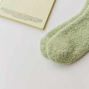 Dettaglio calzini invernali in pile corallo verde chiaro con morbida texture peluche