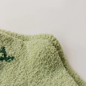 Dettaglio di calzini in pile corallo verde chiaro con morbida trama e ricamo