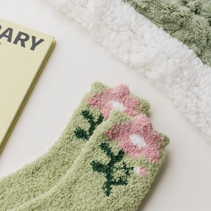 Primo piano di calze in pile corallo verde con ricamo floreale rosa e morbida consistenza