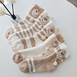 Detailed view of thick coral fleece socks with cute 3D bear motifs and soft pom-poms