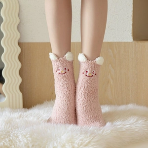 Detail of pink coral fleece socks featuring cute 3D ears and cartoon smiling face embroidery