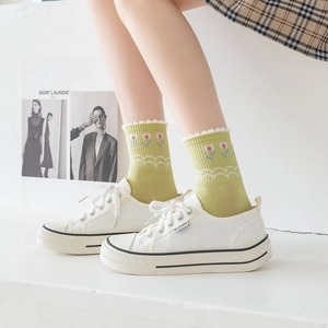 Detail of green mid-calf socks with tulip embroidery and wavy cuffs on canvas shoes