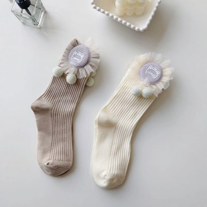 Detail of knit socks featuring cat patches, mesh borders and cute plush pom-poms decoration