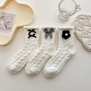 Detail of coral fleece mid-calf socks with black ribbon bows and white flower accents