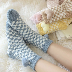 Detail of coral fleece checkerboard socks with 3D plush hearts on white fur rug