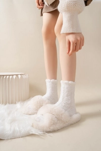 Close-up of beige criss-cross plush slippers worn with warm white knitted socks