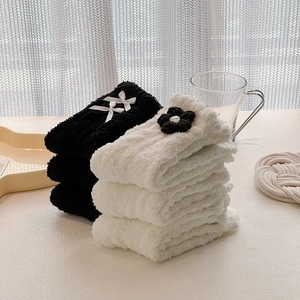 Close-up of fluffy coral fleece socks with bow and flower decorations in black and white