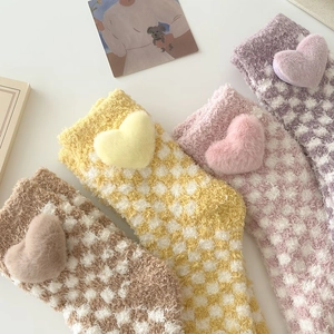 Close-up of checkered coral fleece socks with plush heart details in pastel colors