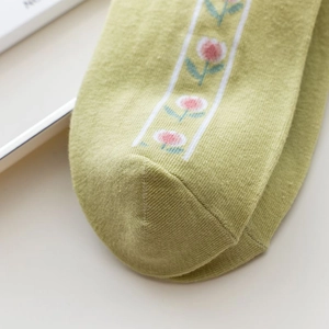 Close-up of knit fabric and floral pattern on light green combed cotton crew socks