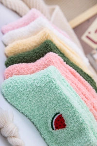 Close-up of fluffy coral fleece socks with cute watermelon embroidery and pastel colors