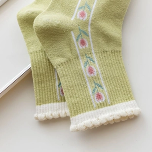 Detail of green cotton socks featuring pink tulip embroidery and white ruffled edges