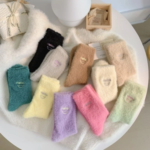 Dettaglio di calze colorate in velluto di visone con ricami di sorrisi e scritte Hello